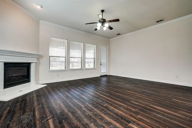 a view of an empty room with wooden floor fireplace and a window