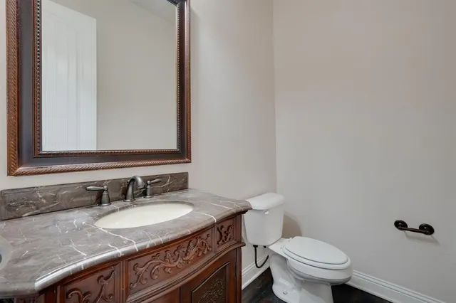 a bathroom with a granite countertop sink a toilet and a mirror