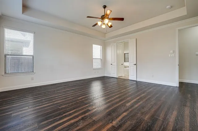 a view of an empty room with a window and wooden floor