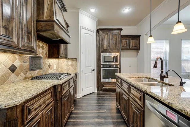 a kitchen with stainless steel appliances granite countertop a sink a stove and a wooden cabinets