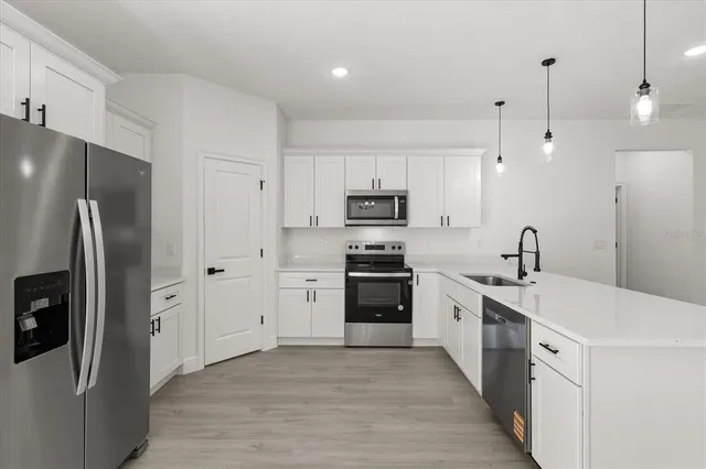 a kitchen with stainless steel appliances granite countertop a refrigerator a sink a stove and oven with wooden floor