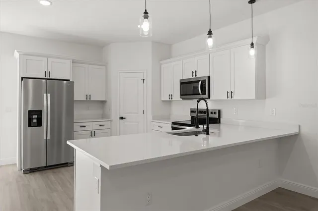 a kitchen with a refrigerator a microwave a stove and a sink with wooden floor