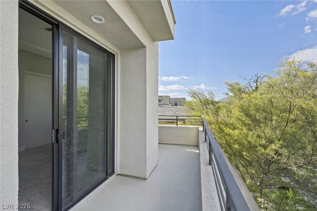 4208 Lapis Ridge Court Las Vegas, NV 89135 - Photo 33 of 61 Sliding glass doors open onto a private balcony overlooking lush treetop views.