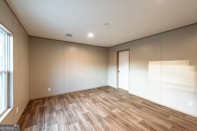 a view of empty room with wooden floor and fan