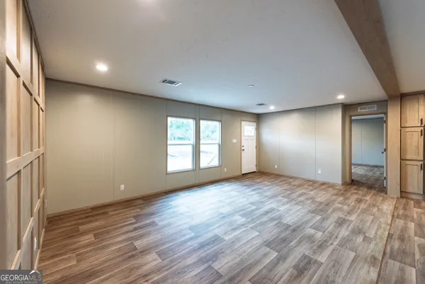 an empty room with wooden floor and windows