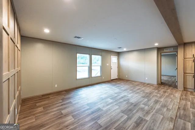 an empty room with wooden floor and windows