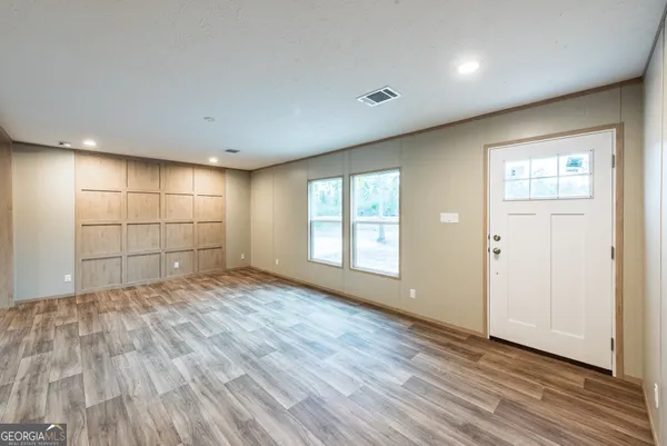an empty room with wooden floor and windows