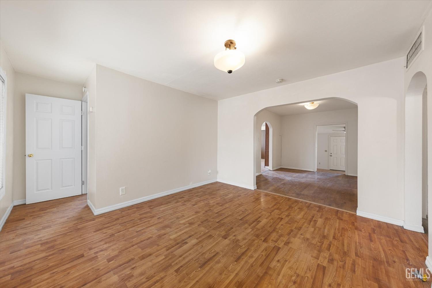 Undisclosed Address Bakersfield, CA 93308 - Photo 9 of 32 an empty room with wooden floor and mirror