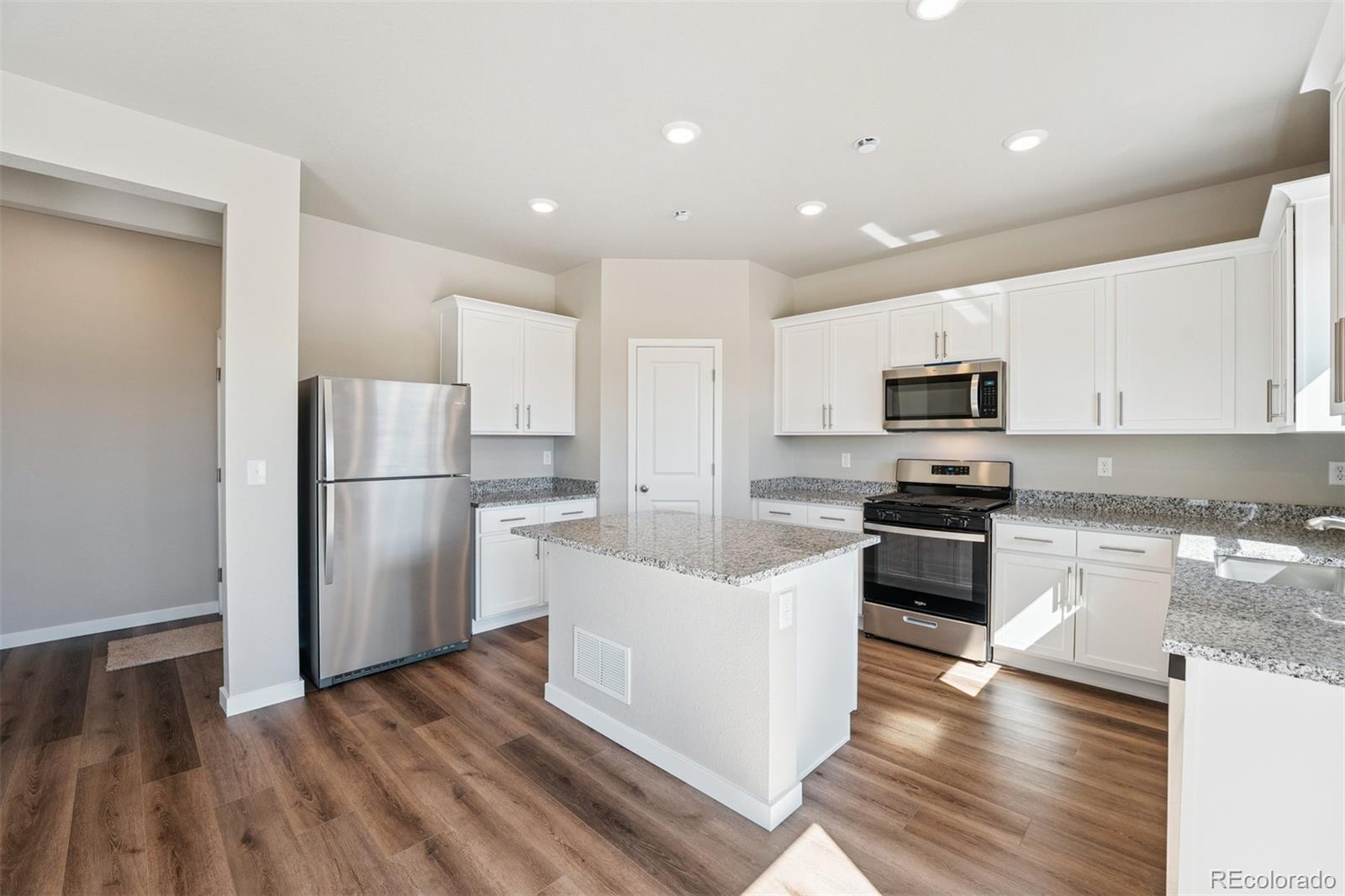 2160 Christina Street Fort Lupton, CO 80621 - Photo 5 of 41 a kitchen with stainless steel appliances granite countertop a refrigerator a stove top oven a sink and dishwasher with wooden floor
