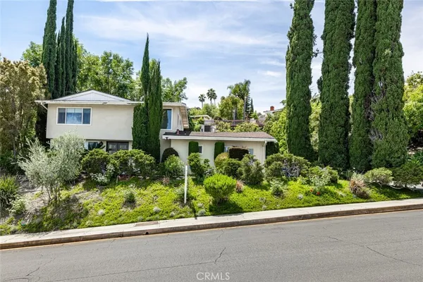 a front view of a house with a yard and potted plants
