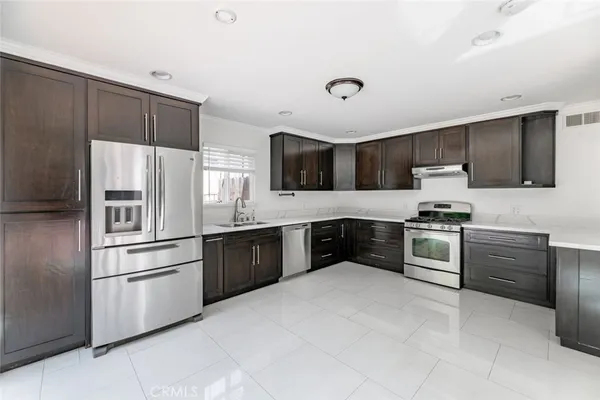 a kitchen with granite countertop a refrigerator and a stove top oven