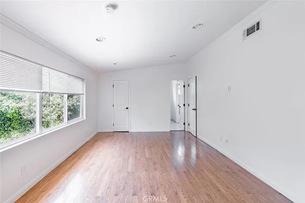 a view of an empty room with wooden floor and windows