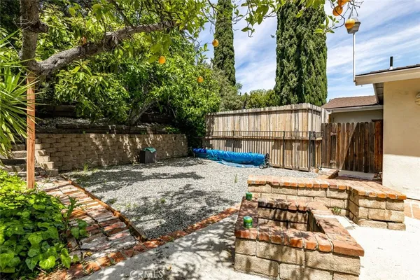 a view of a backyard with wooden fence and large trees