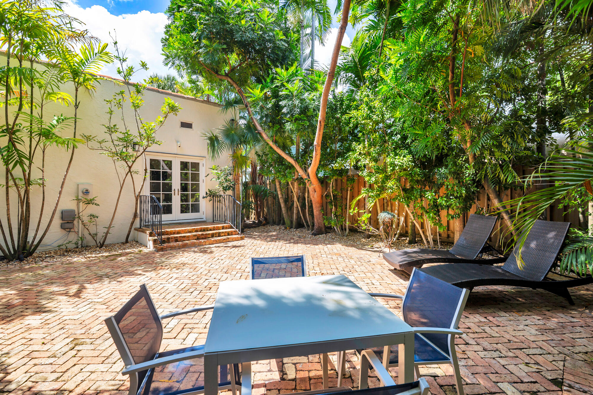 205 Westminster Road West Palm Beach, FL 33405 - Photo 25 of 37 a view of a patio with table and chairs with wooden fence and large trees