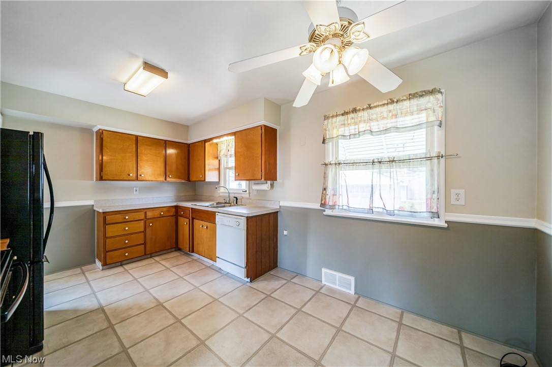 648 Pendley Road Willowick, OH 44095 - Photo 8 of 35 Kitchen featuring brown cabinets, light countertops, light tile floors, white dishwasher, black refrigerator, and ceiling fan