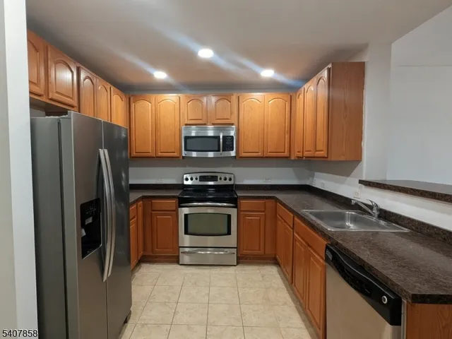 a kitchen with stainless steel appliances granite countertop a refrigerator sink and stove
