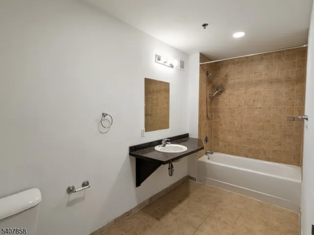 a bathroom with a granite countertop sink a toilet and shower