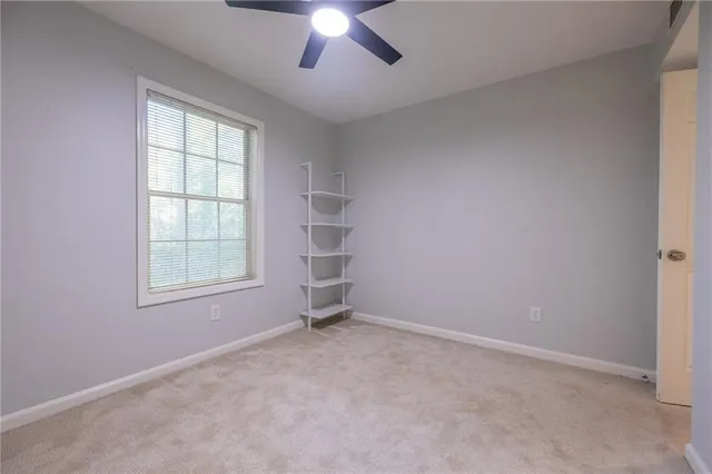an empty room with chandelier fan and windows