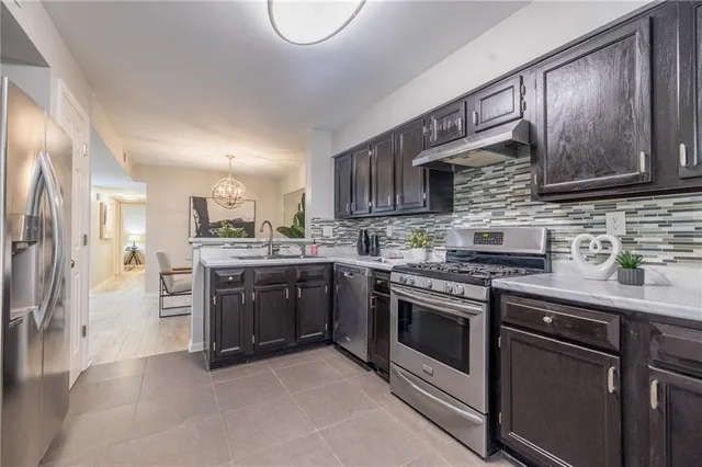 a kitchen with stainless steel appliances granite countertop a stove top oven a sink and a microwave