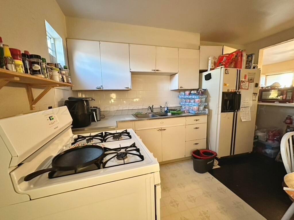 4611 South Ong Street Amarillo, TX 79110 - Photo 5 of 11 a kitchen with a refrigerator and a stove top oven