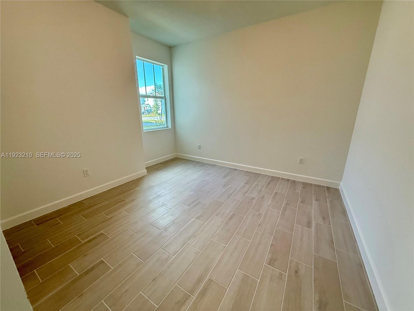 19600 Whispering Creek Road, Unit 19600 West Palm Beach, FL 33470 - Photo 13 of 26 an empty room with wooden floor and windows