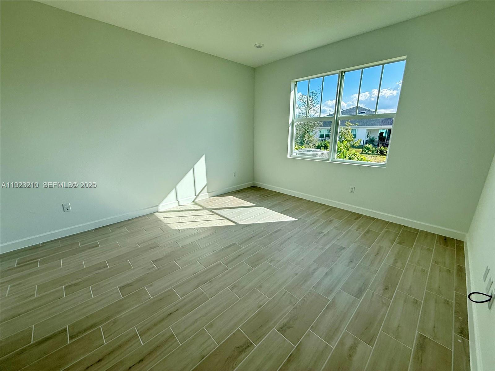 19600 Whispering Creek Road, Unit 19600 West Palm Beach, FL 33470 - Photo 5 of 26 an empty room with wooden floor and windows
