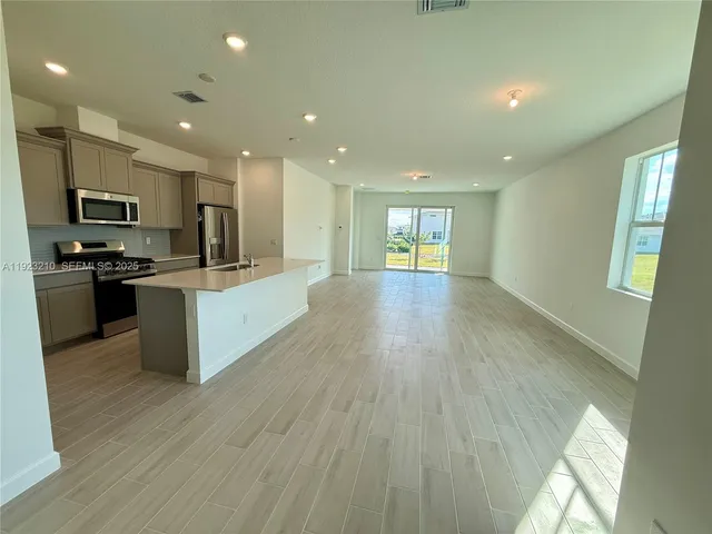 a large kitchen with stainless steel appliances granite countertop a stove a sink dishwasher and a microwave oven on the wooden floor