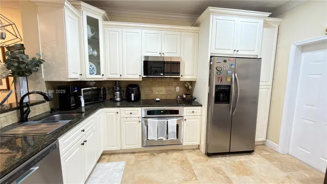 a kitchen with stainless steel appliances granite countertop a refrigerator and a stove top oven