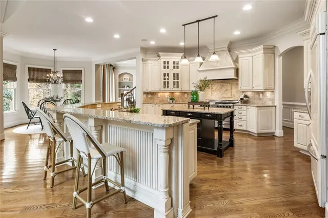 a kitchen with stainless steel appliances kitchen island granite countertop a stove top oven a sink a dining table and chairs