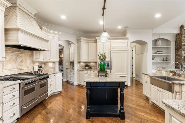 a kitchen with stainless steel appliances kitchen island granite countertop a stove a sink a refrigerator and cabinets