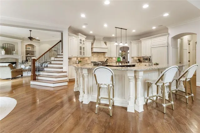 a kitchen with stainless steel appliances granite countertop a kitchen island hardwood floor and a sink