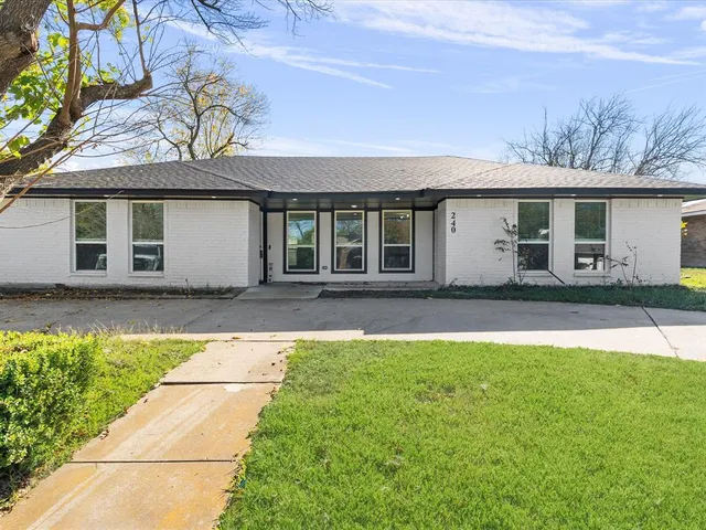 a front view of a house with a garden and trees