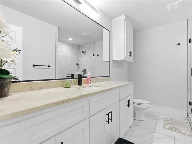 a bathroom with a granite countertop sink mirror and toilet