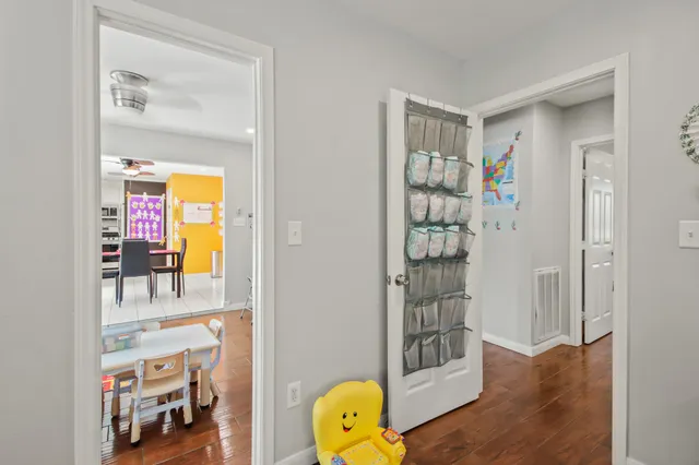 a view of a hallway with wooden floor and a living room