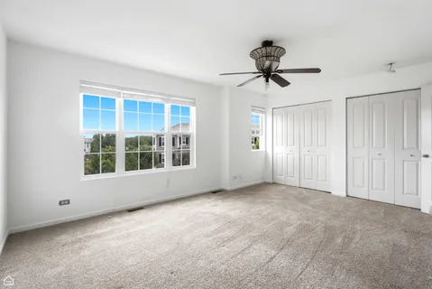 a view of a room with a ceiling fan and windows