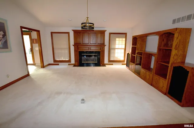 a view of an empty room with fireplace and a window