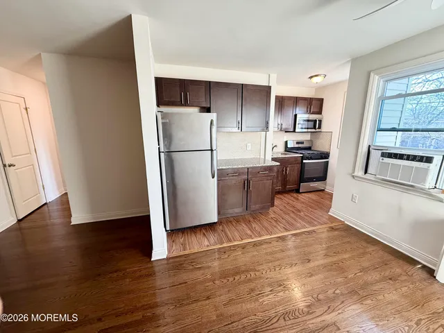 a kitchen with stainless steel appliances a refrigerator a sink a stove a microwave and wooden floor