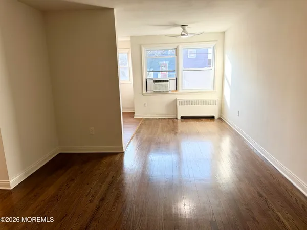 a view of an empty room with a window and wooden floor