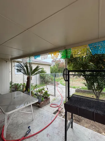 a patio with table and chairs and potted plants