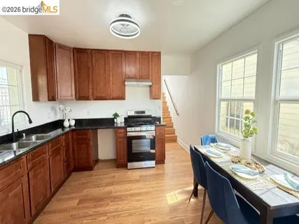 a kitchen with granite countertop a stove a sink dishwasher and cabinets with wooden floor