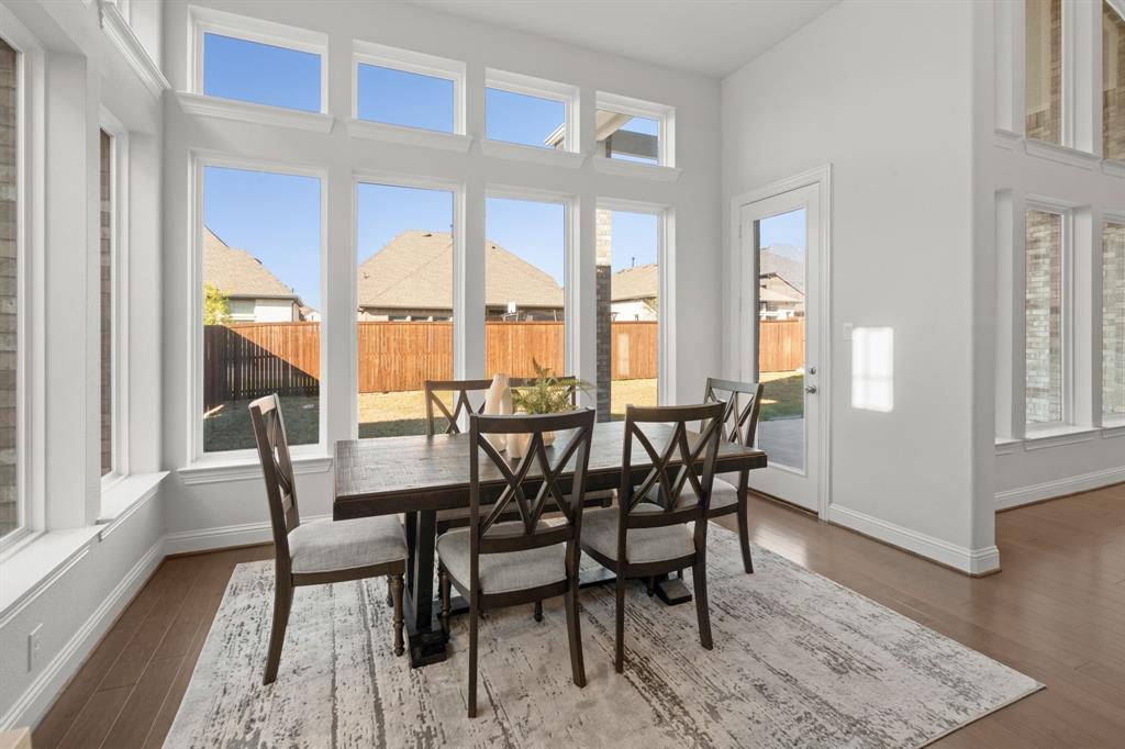 1320 Cartona Road Fate, TX 75087 - Photo 12 of 35 Spacious nook secondary dining room featuring multiple large picture windows, a glass-paneled exterior door, and wood-finish flooring