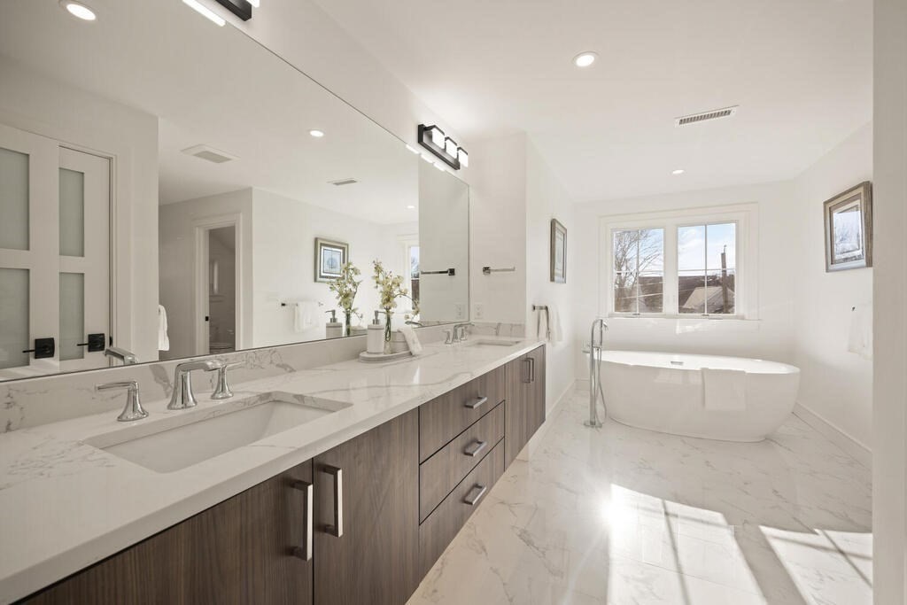 40 Bridge Street Lexington, MA 02421 - Photo 27 of 42 a bathroom with a double vanity sink a large mirror and a bathtub
