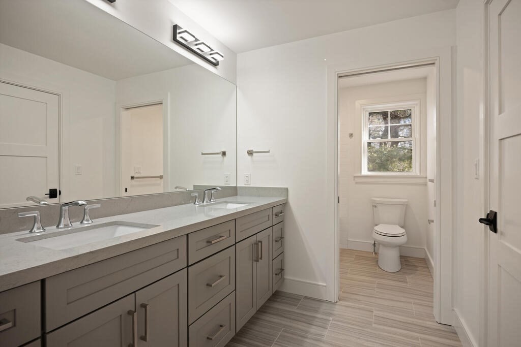 40 Bridge Street Lexington, MA 02421 - Photo 31 of 42 a bathroom with a granite countertop toilet a sink a mirror and a window