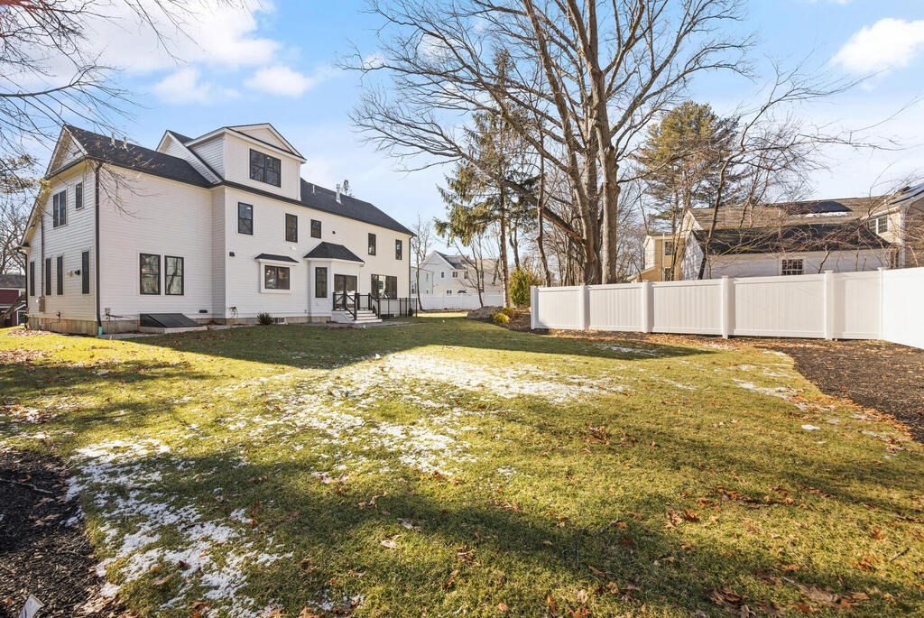 40 Bridge Street Lexington, MA 02421 - Photo 38 of 42 a view of a white house with a large pool with lawn chairs and wooden fence