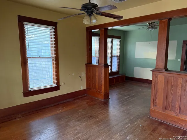 an empty room with wooden floor closet and windows
