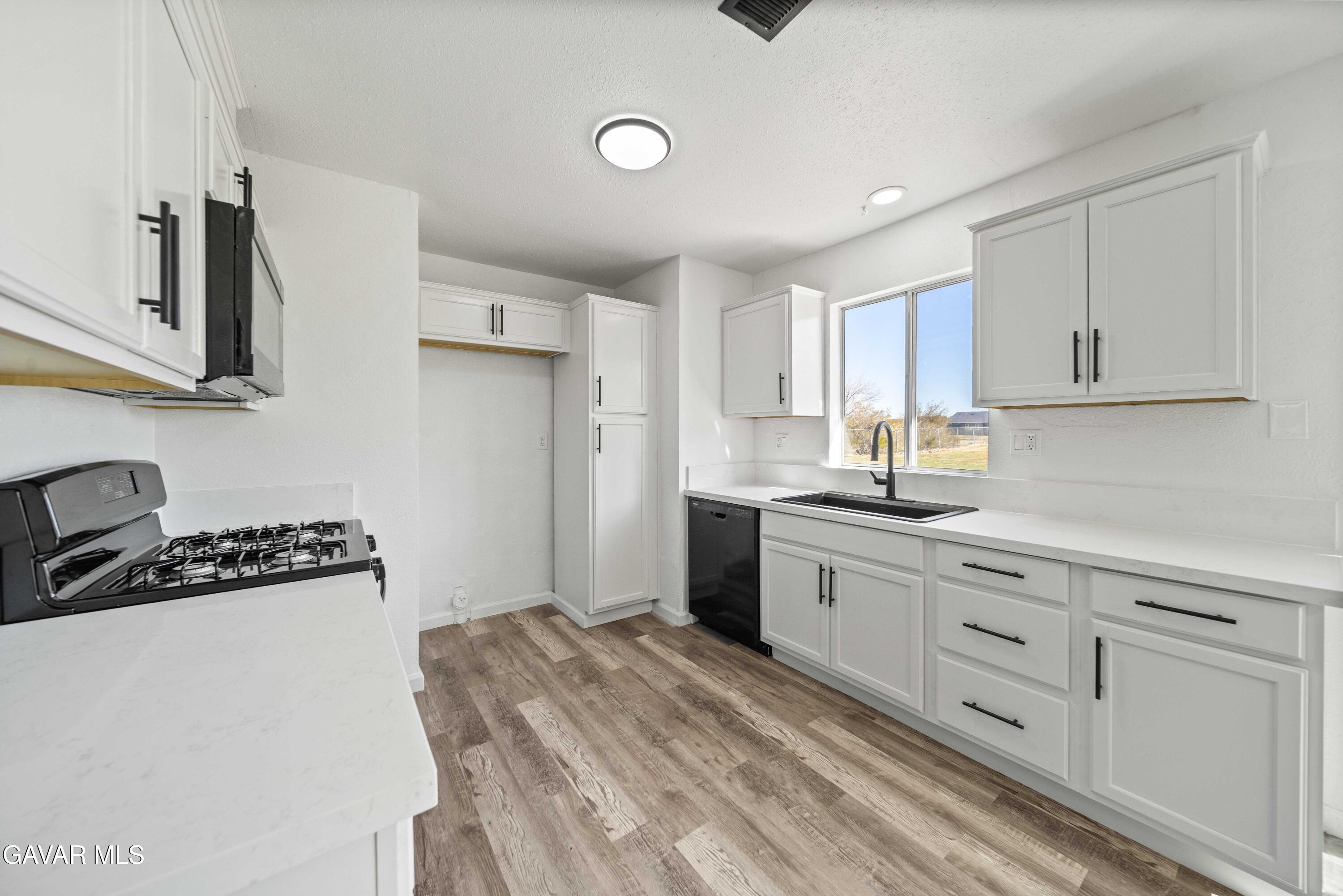 40054 Ridgemist Street Palmdale, CA 93591 - Photo 8 of 21 a kitchen with granite countertop a sink a stove and cabinets