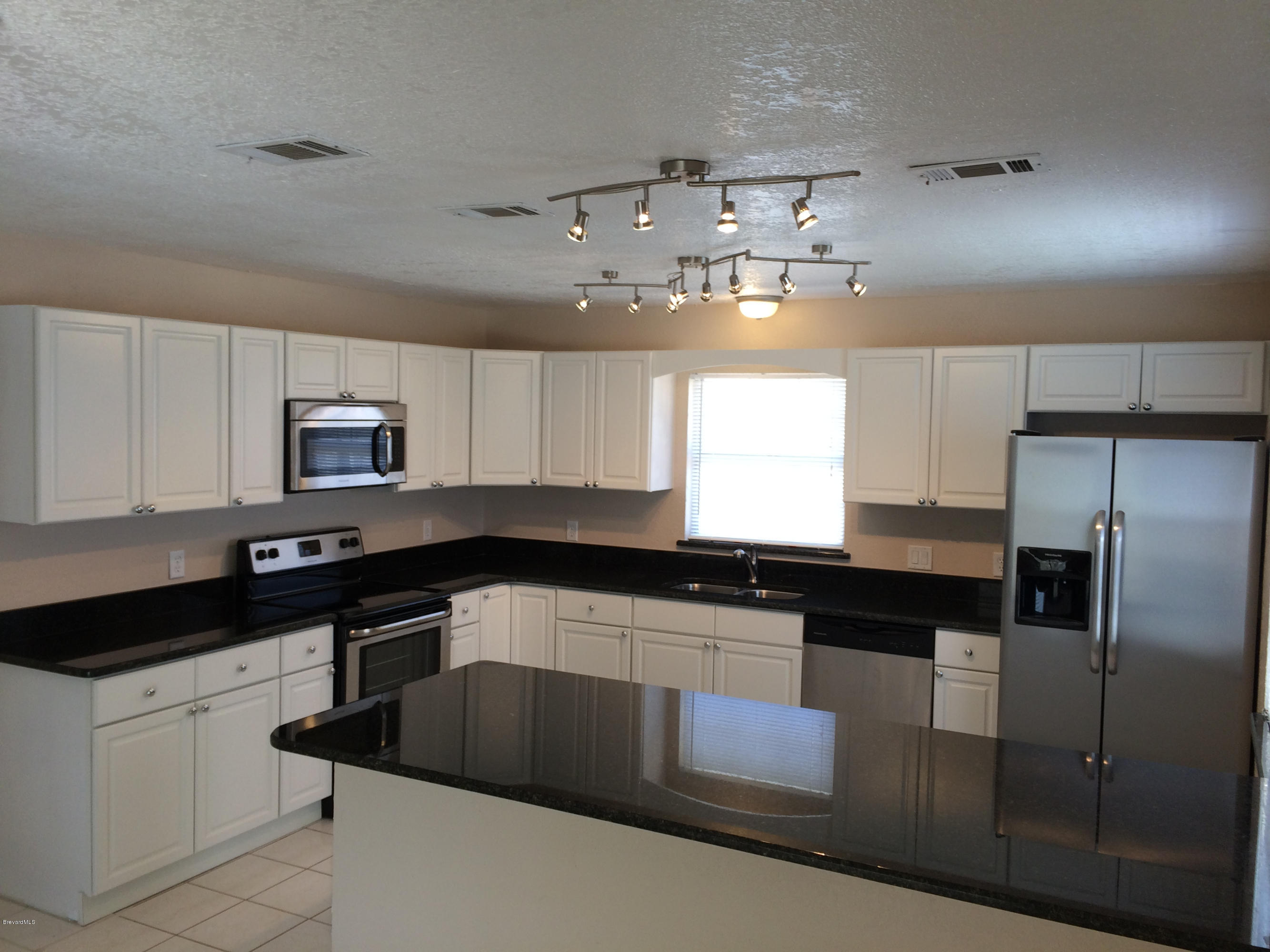a kitchen with granite countertop a sink a counter space stainless steel appliances and cabinets