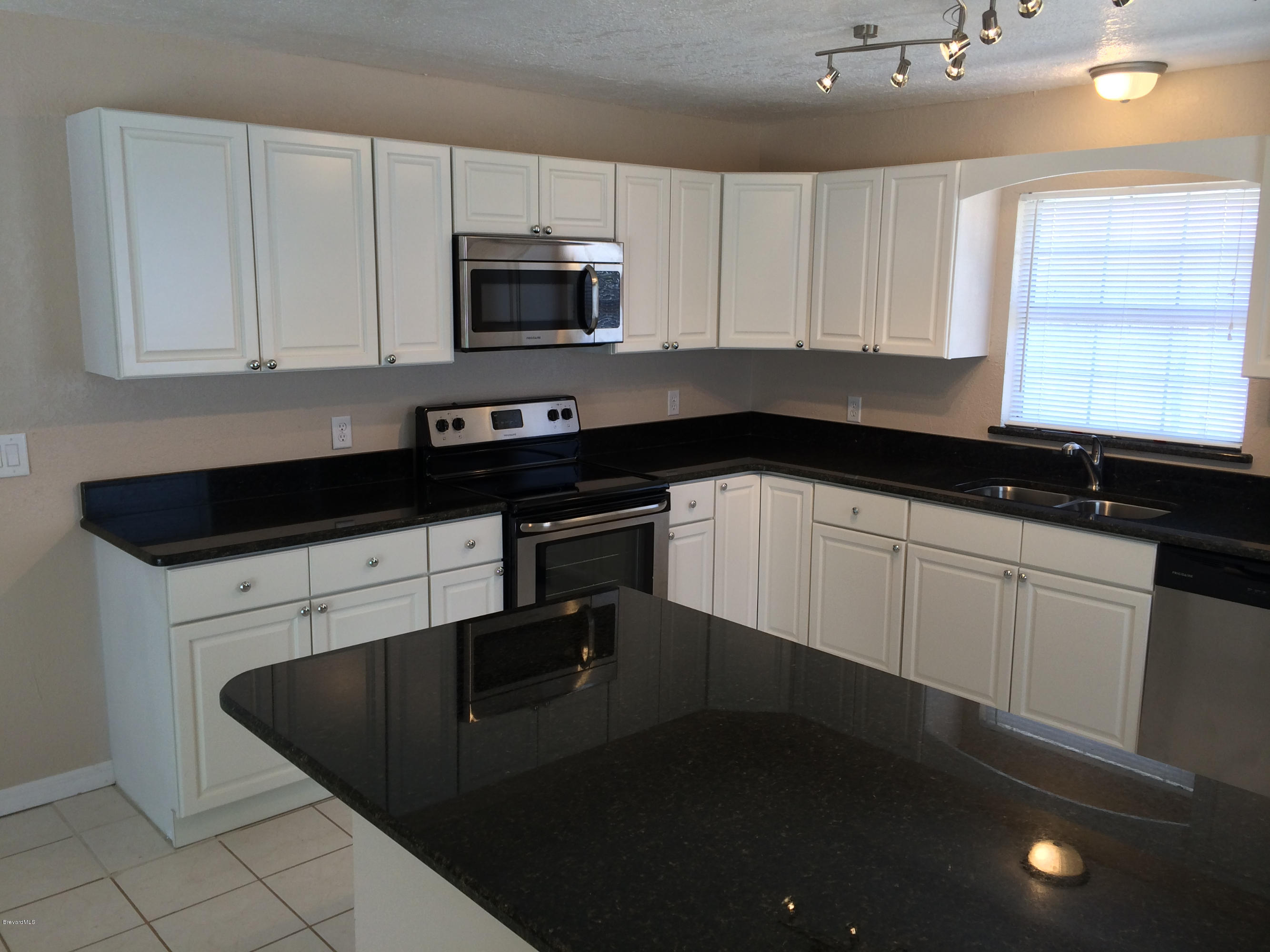 6965 Bryant Road Cocoa, FL 32927 - Photo 2 of 12 a kitchen with white cabinets a sink and appliances