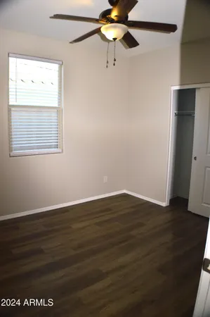 a view of an empty room with wooden floor and closet