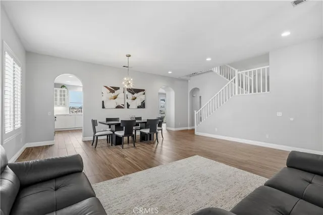 a living room with furniture and a dining table with wooden floor